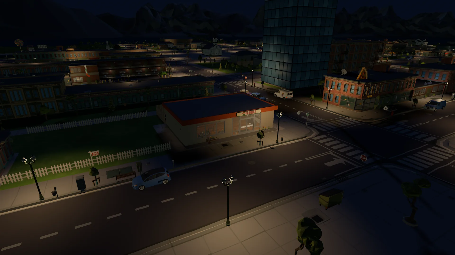 The same corner at night under the street lamps, the church and town lights behind it